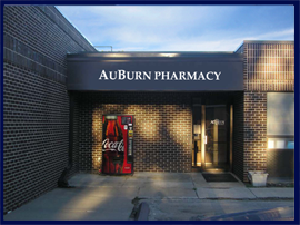This picture shows the AuBurn Pharmacy Carbondale Location. It is a dark brick building with a dark blue awning on it